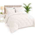 Neatly made bed with white bedding, pillows, and a lamp on a nightstand.
