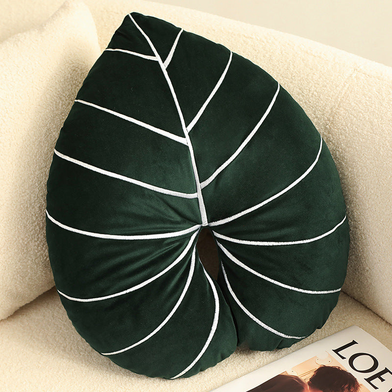 Plush monstera leaf pillow on sofa